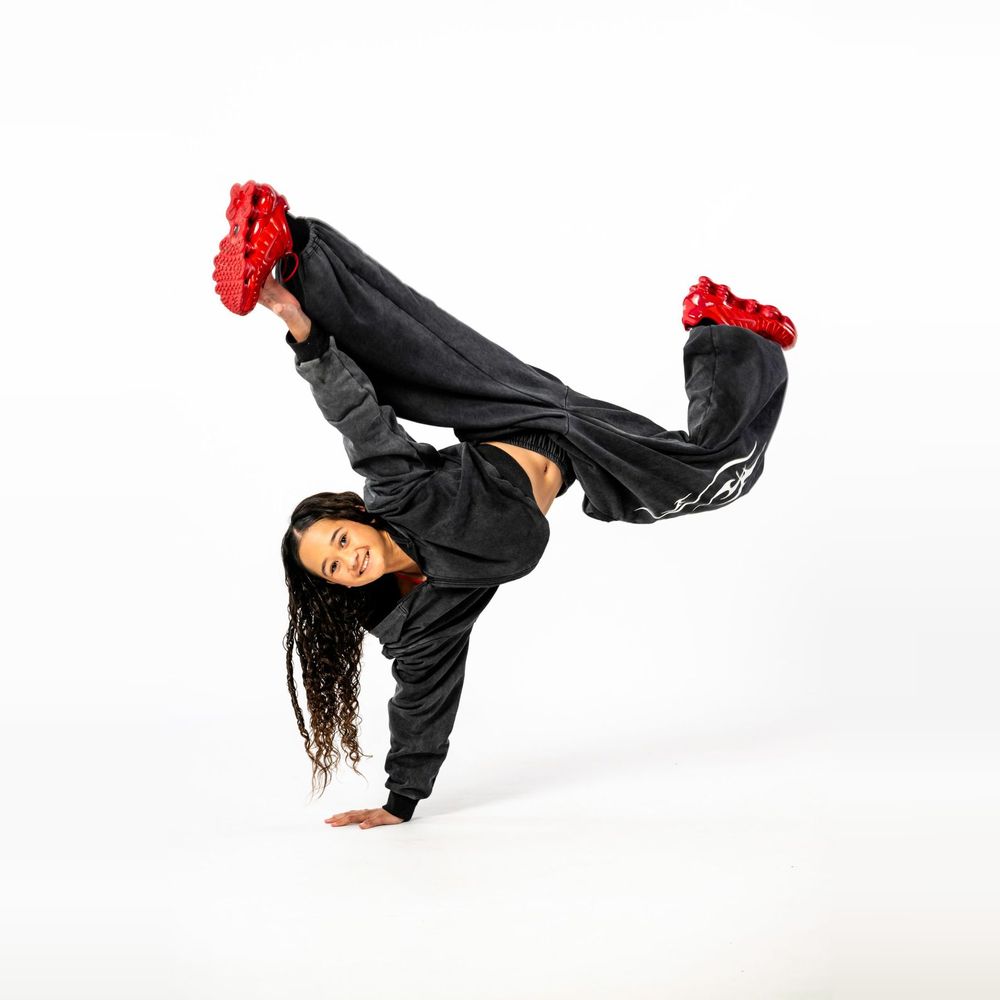 Hip hop dancer in a one-hand freeze in red sneakers