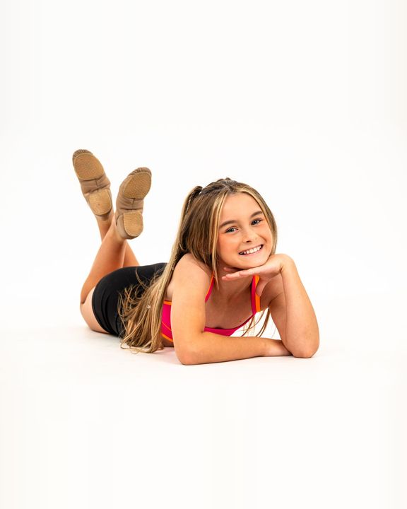 Young dancer lying on the floor, chin in hands, smiling