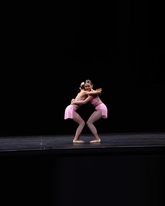 Two dancers in pink performing a duet on stage
