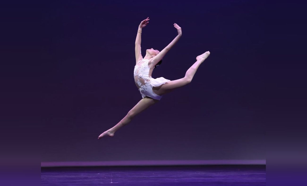 Dancer in a split leap on stage under purple lights