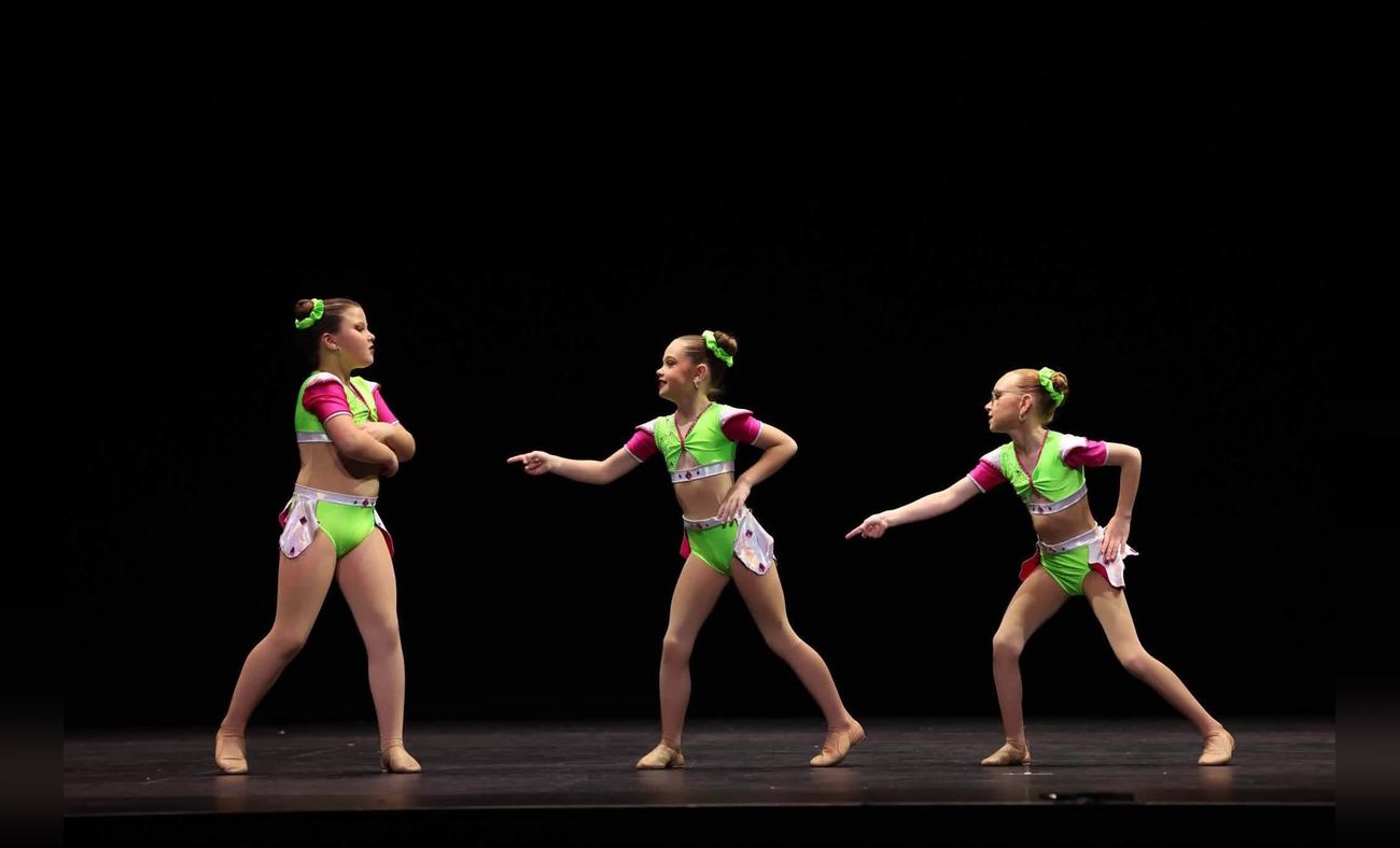 Three dancers in green performing on stage