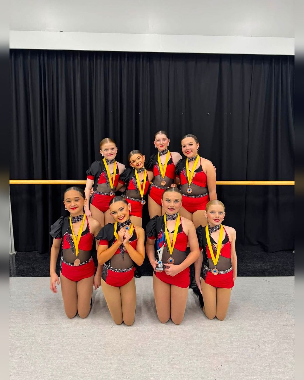 TDC troupe in red costumes showing their competition medals