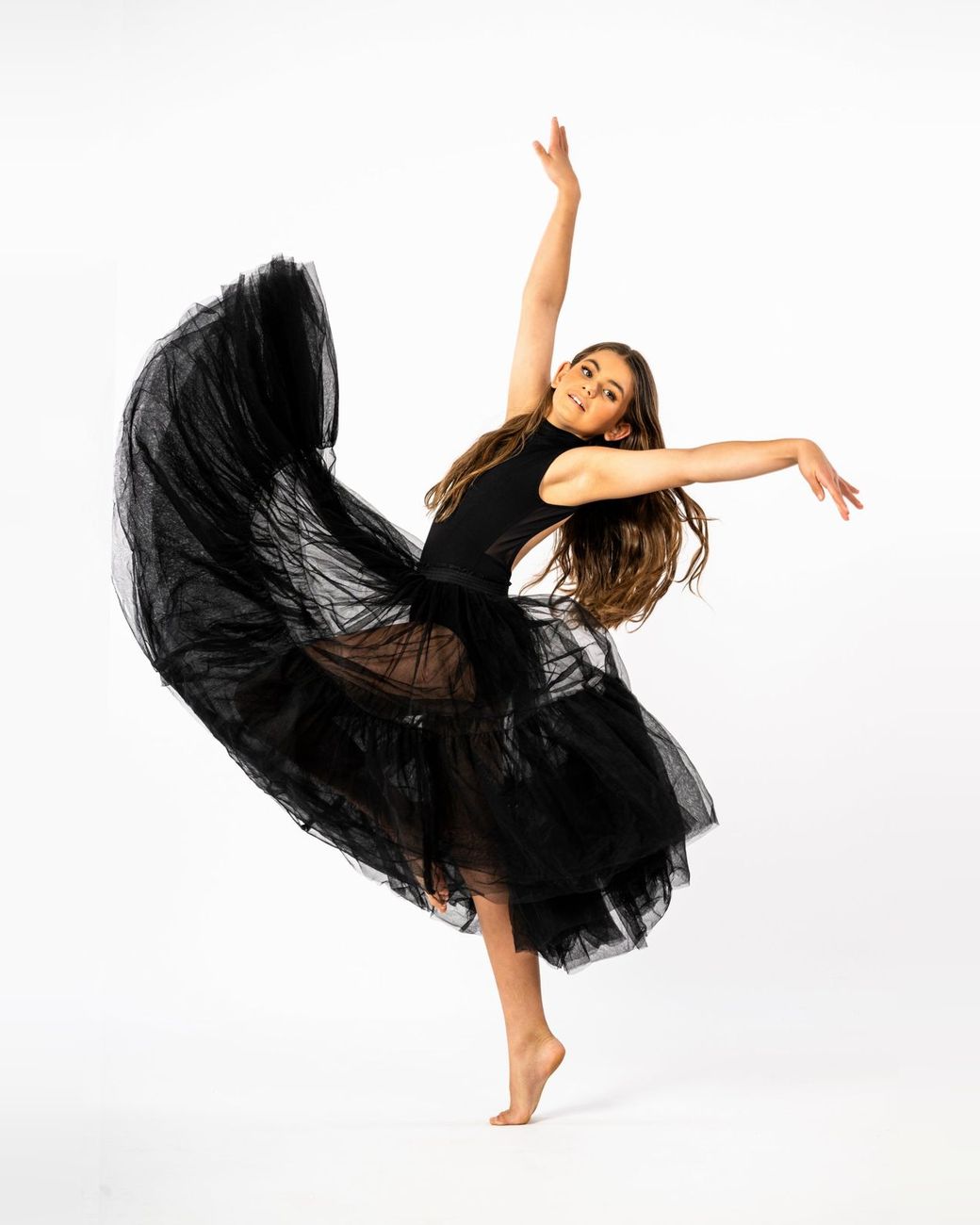 Dancer in a flowing black tulle skirt, arms raised