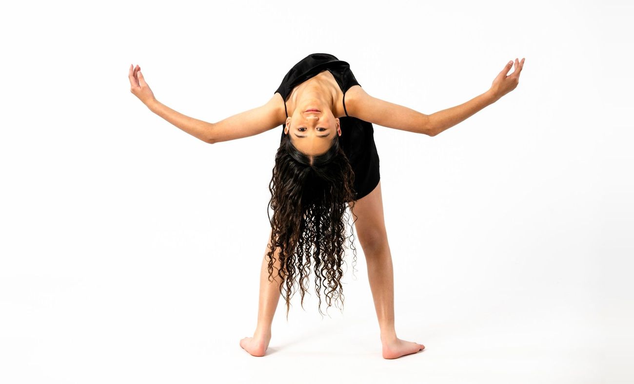 Dancer bending forward, looking upside down with arms outstretched